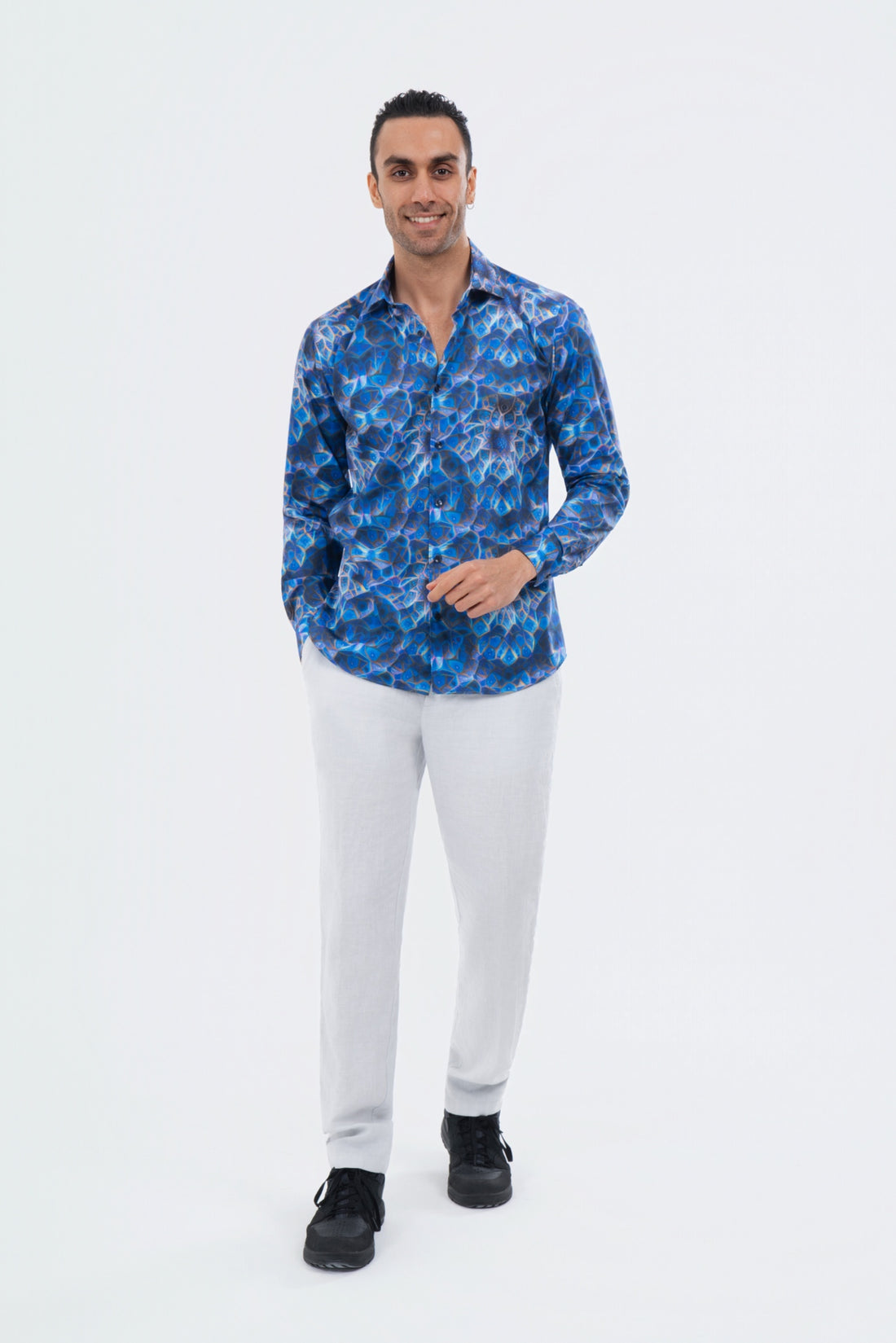 Male model wearing a cobalt blue abstract-print shirt with white trousers.
