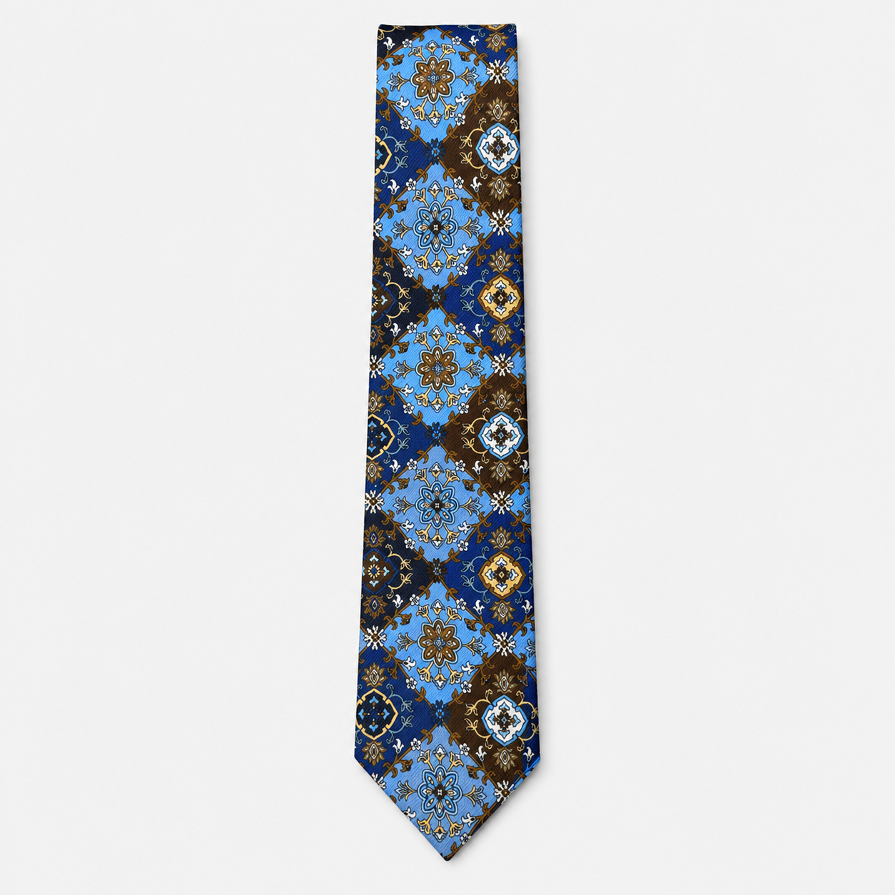 The Bergamo Tie, an ornate navy and light blue silk tie with brown, gold and white medallions on a light grey background.
