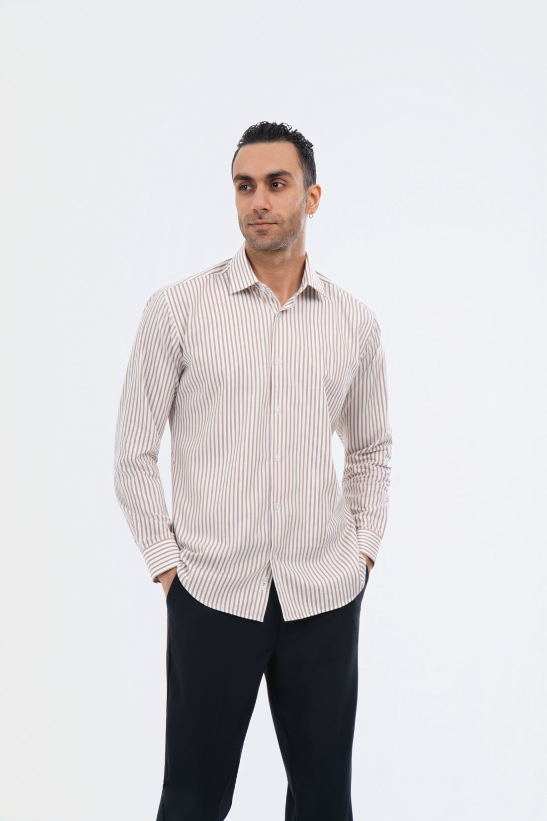 Male model wearing a crème striped shirt with black trousers in the studio.