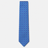 The Ferrara Tie, a royal blue silk tie with turquoise, lavender and white geometric motifs on a light grey background.