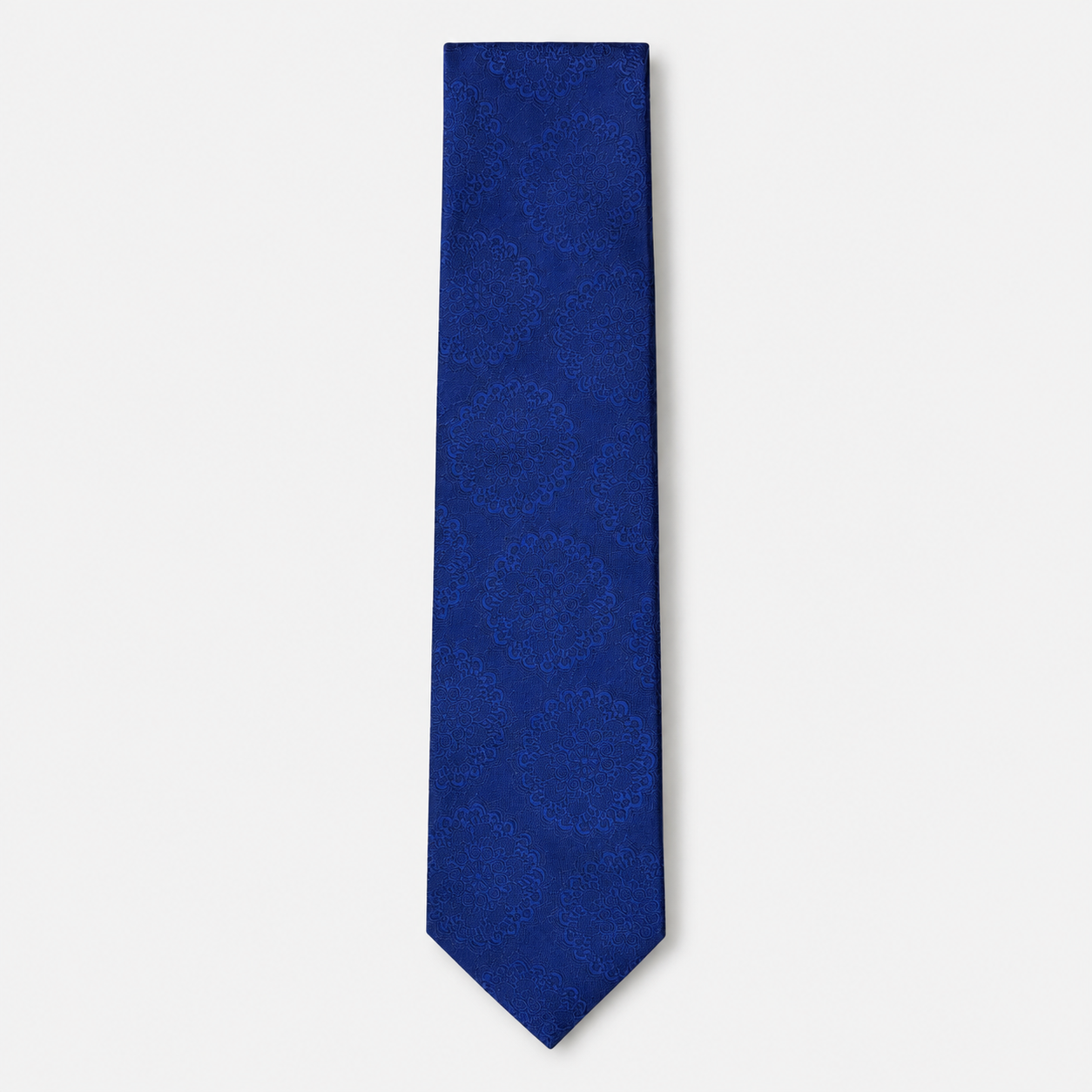 The Livorno Tie, a royal blue silk tie with a tonal floral medallion jacquard on a light grey background.