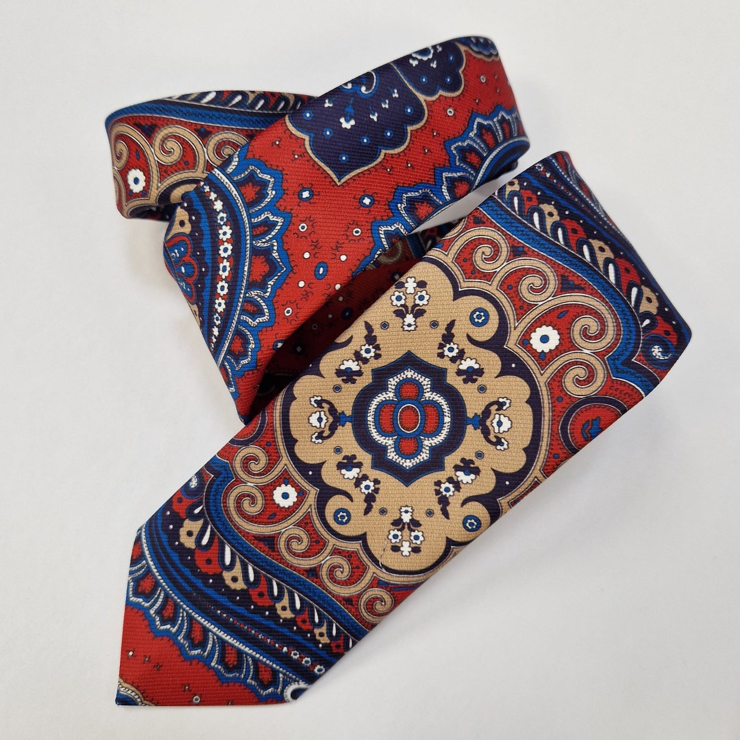 Red, blue and cream medallion paisley silk tie, loosely folded.