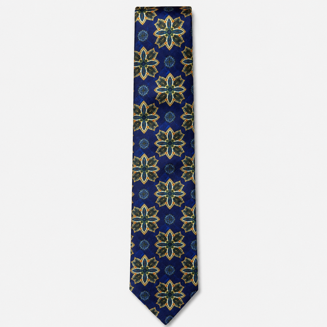The Siracusa Tie – royal blue, gold and teal floral medallion silk tie on a light grey background