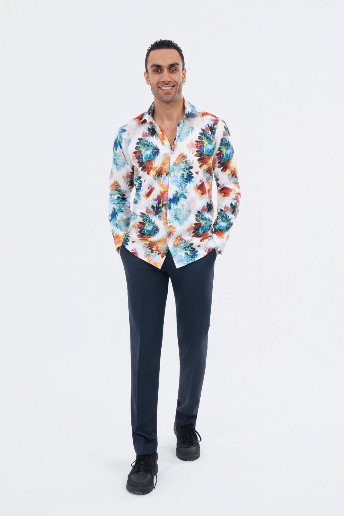 Male model wearing a white multicolour tropical-print shirt with black trousers.